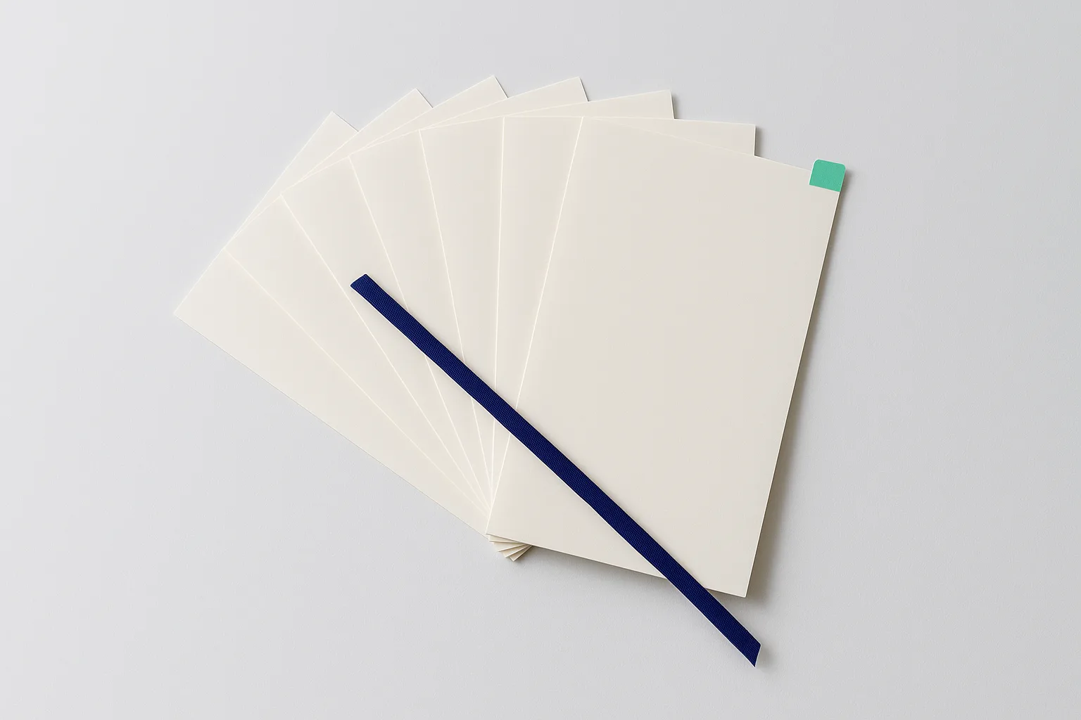 A fan of crisp blank documents with a ribbon marker laid across them